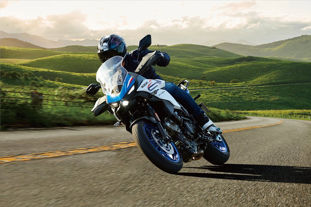 A Suzuki SV-7GX rider rounds a corner on a hillside road.