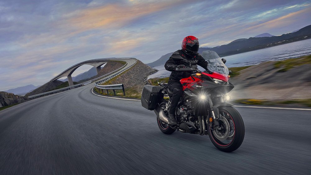 A CB1000GT rider travels alongside a lake.