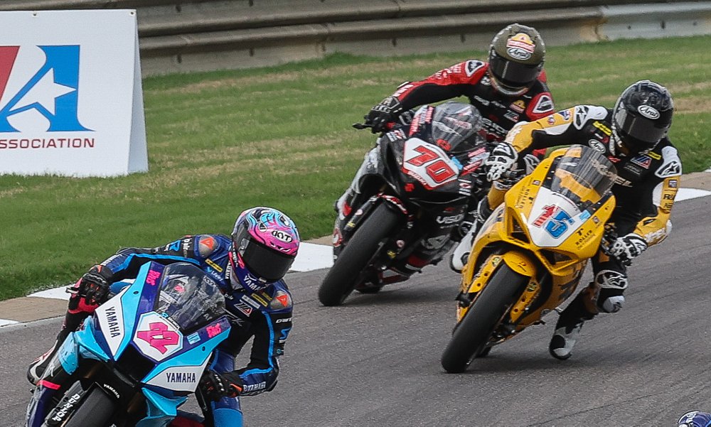 three riders in a professional race, all leaning into a corner