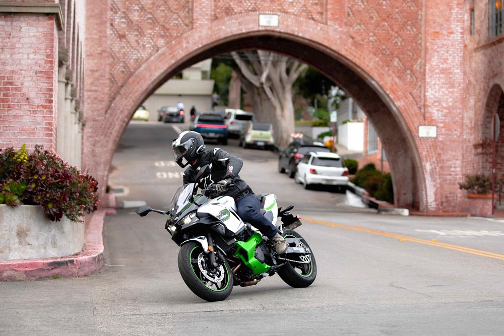 rider going around a corner in the city on a green and silver Ninja with a brick arch in the background