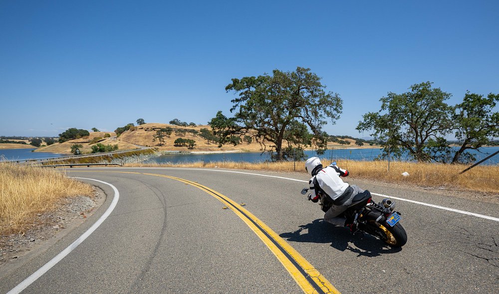 Lance riding through a curve above a lake in the dry grassland of California