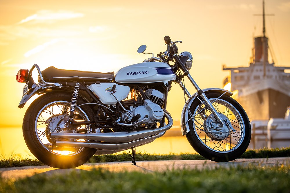 1969 Kawasaki H1 Mach III parked with the Queen Mary in the background at sunset.