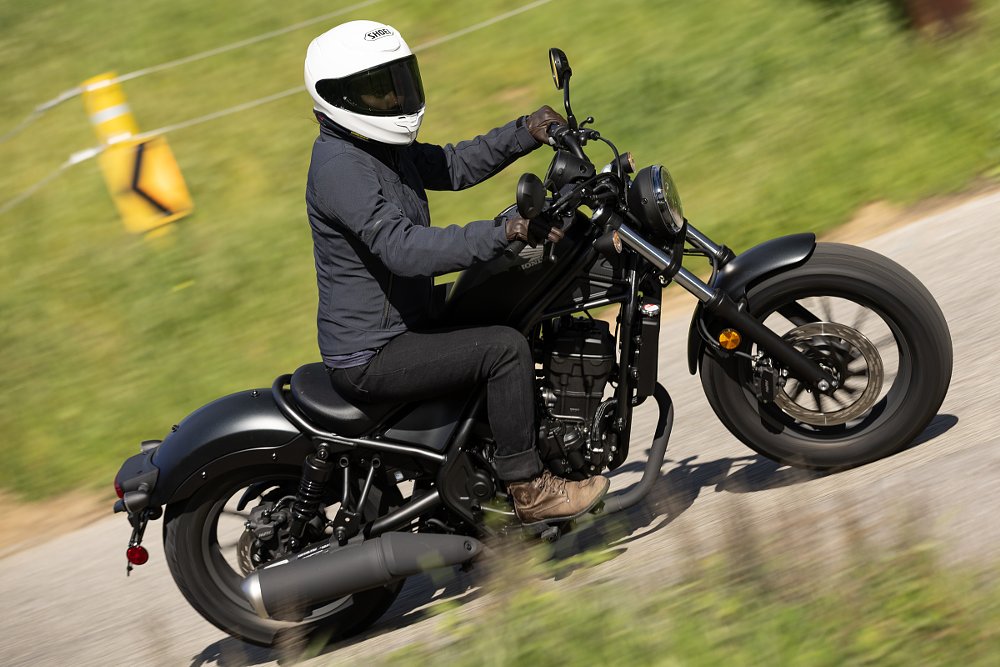 rider on the Rebel 300 on a small lane surrounded by tall grass