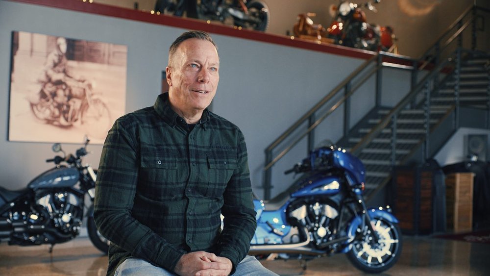 Mike Kennedy in front of two Indian motorcycles in a showroom