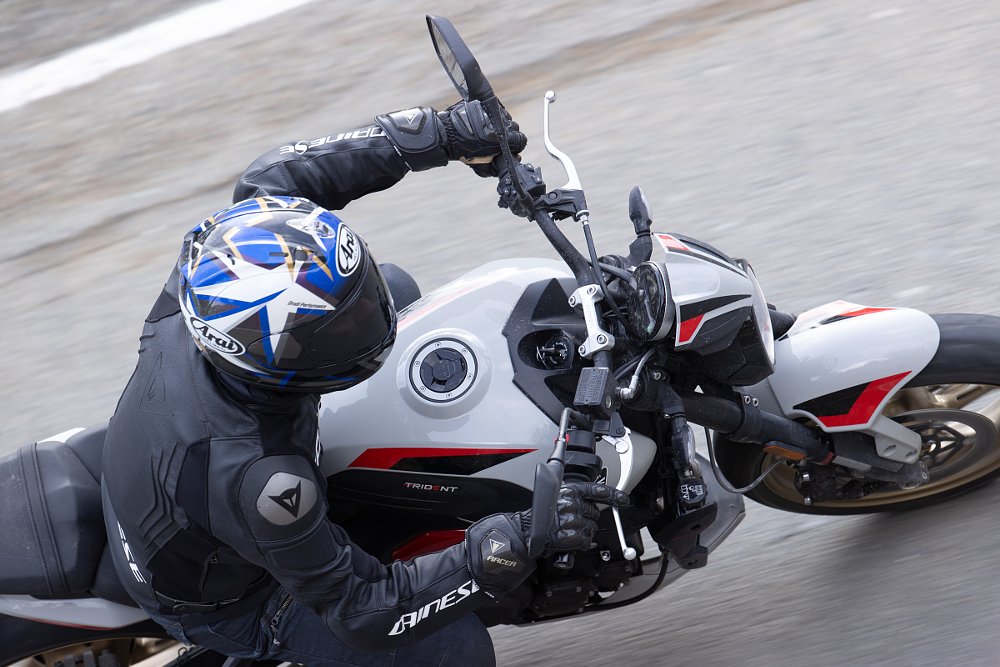 close view from above of the rider leaned over the tank of the Trident 800 while riding through a curve