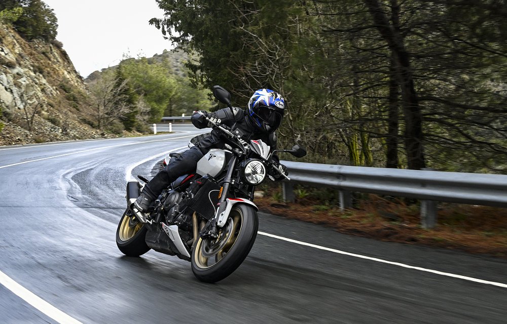 riding the Trident 800 through a mountain curve that is damp from rain
