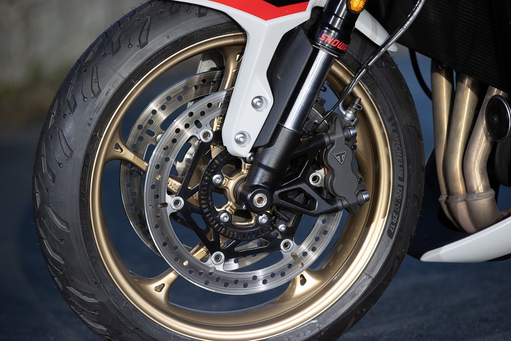 close view of the front wheel with Triumph-branded brake components and Showa inverted fork
