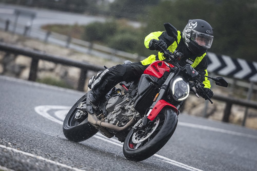 front three-quarters view of the rider on the Monster on a wet, curvy road