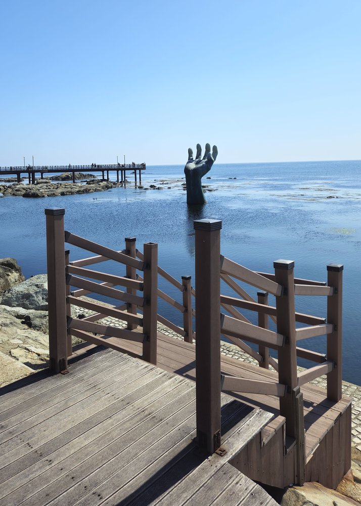 large sculpture of a hand rising from the water