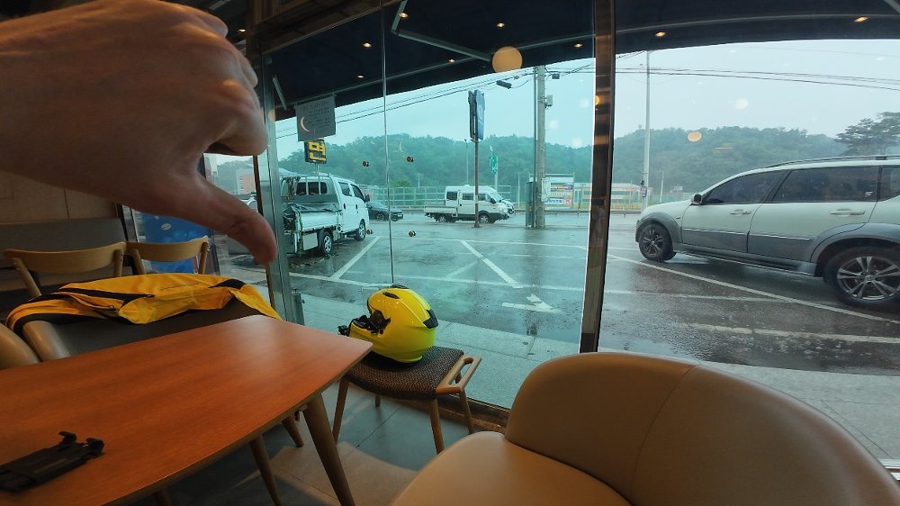 view from inside a building of rain pouring on the parked motorcycle outside