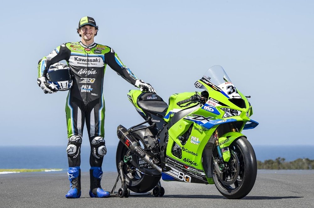 Garrett Gerloff posing with his green 2026 Kawasaki race bike with blue and white accents in front of the ocean at Phillip Island