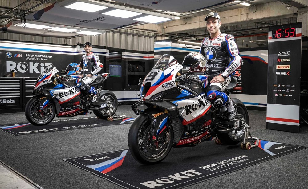 Oliveira and Petrucci posing on their BMW race bikes in the garage