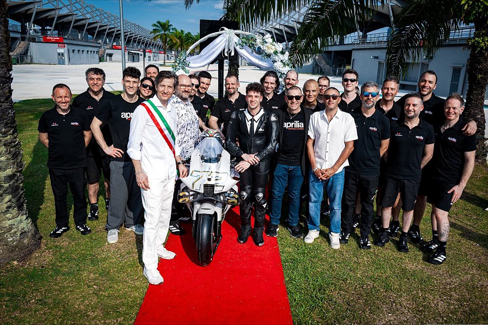 A promotional shot of the Aprilia race team along with rider Marco Bezzecchi and the RS-GP26 race bike.