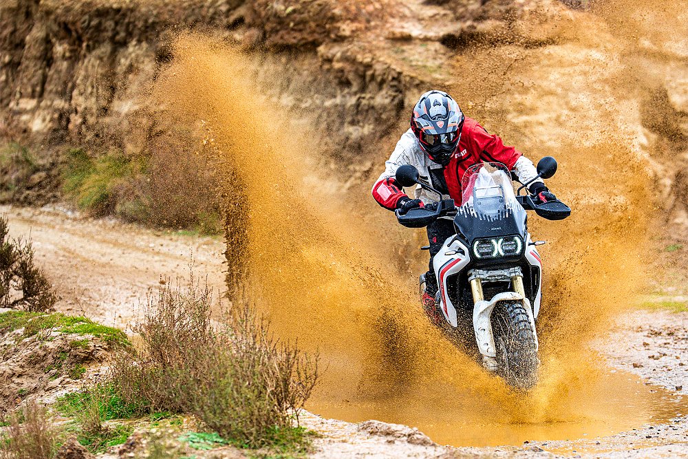 A rider splashes through a puddle while riding the DesertX off-road.