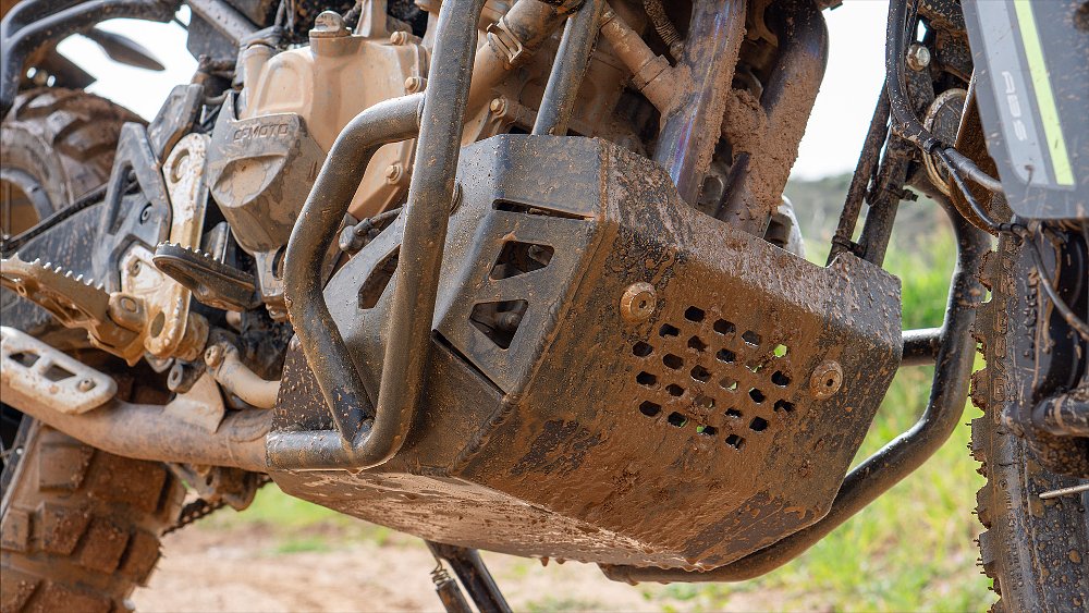 A close-up of the Ibex 450's mud-covered bash plate.