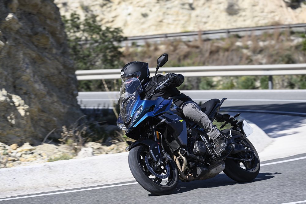 riding the blue Tiger Sport 660 through a mountain curve in Spain