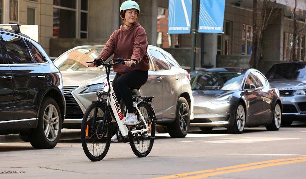 A woman riding an electric bicycle along a city street.