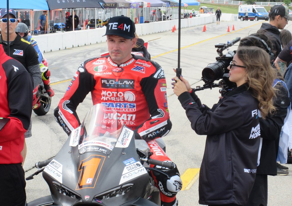Beaubier waiting for the start of the race, sitting on his motorcycle, with people milling around on the grid