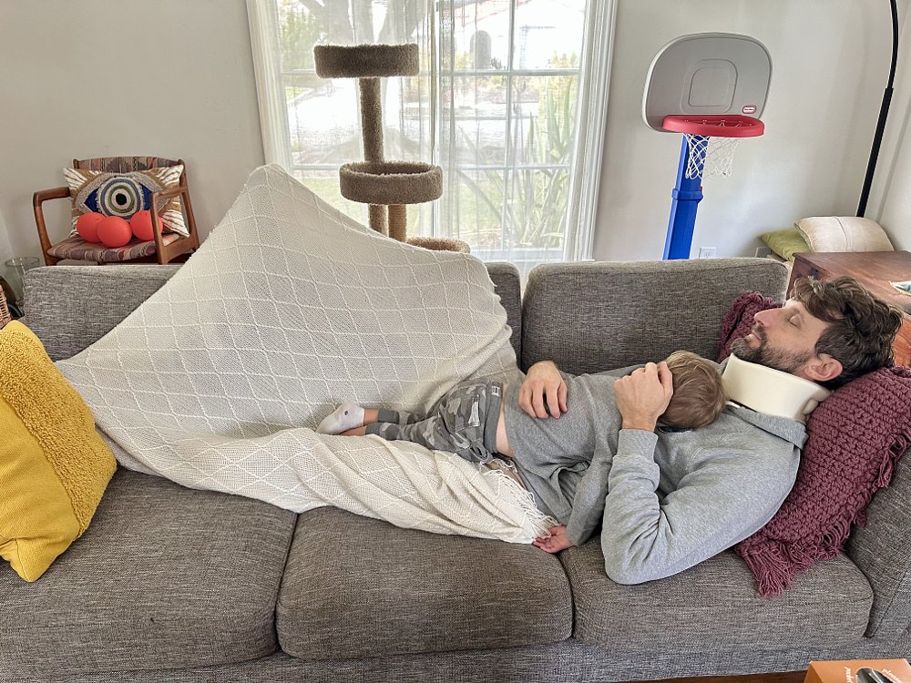 Zack Courts asleep on a couch with his son.