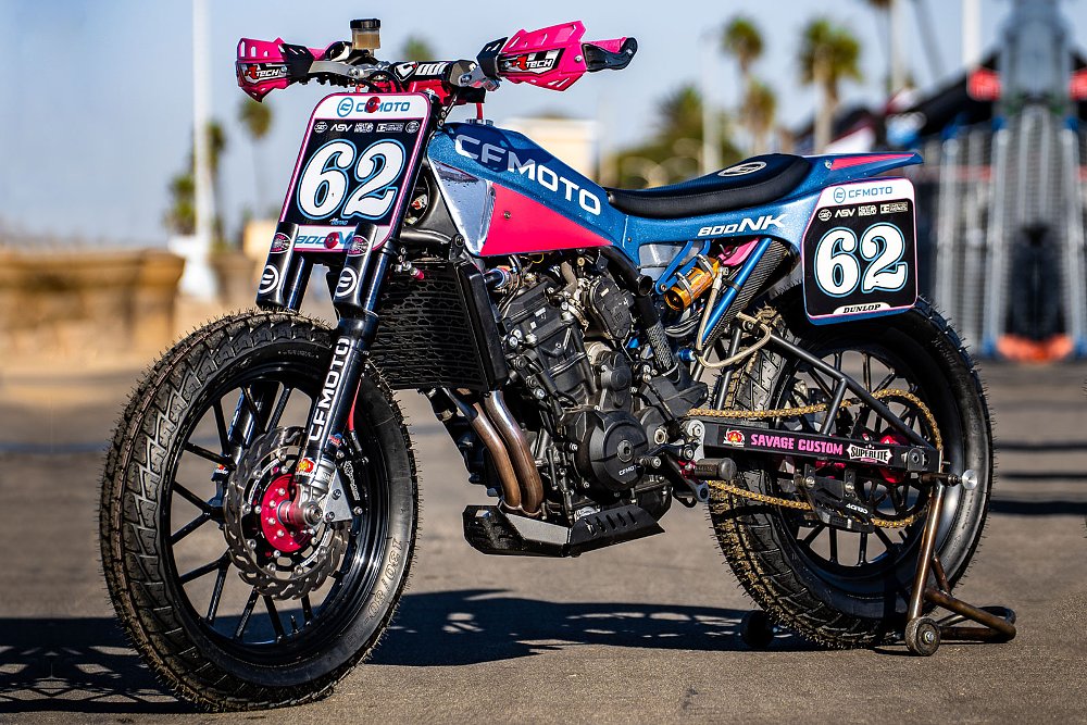 the blue and pink flat-track race bike on a stand at the track