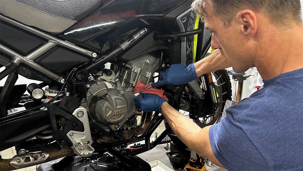 Ari Henning pries open the Ibex 450's clutch cover with a flathead screwdriver.