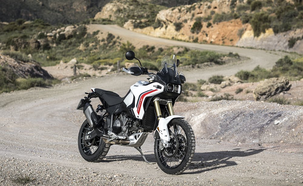 The white DesertX parked on a dirt road in the mountains, side view