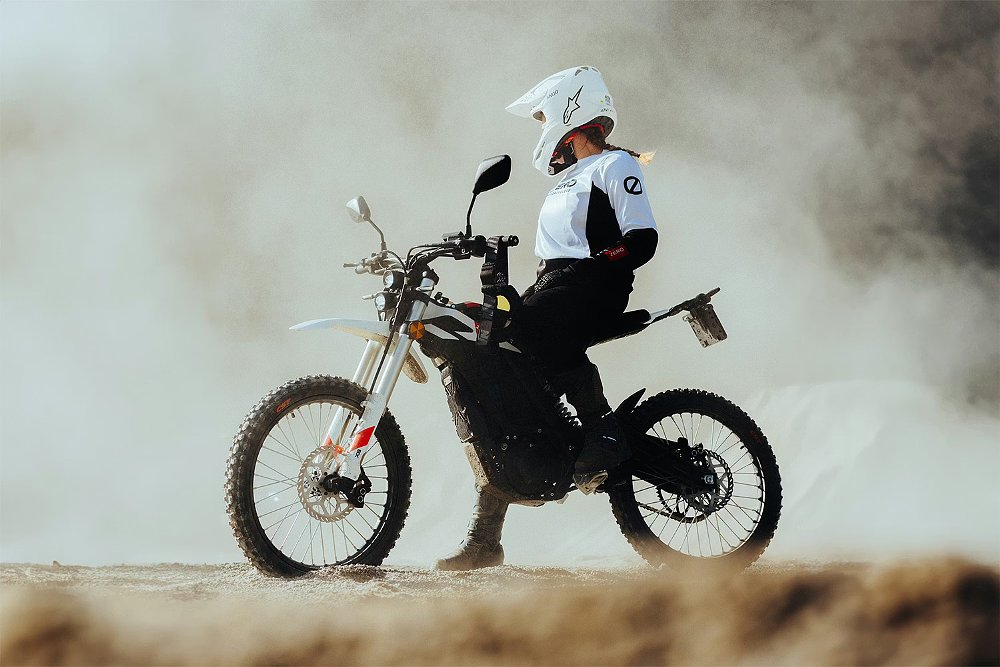 A woman rider waits trailside, sitting on the Zero XB.