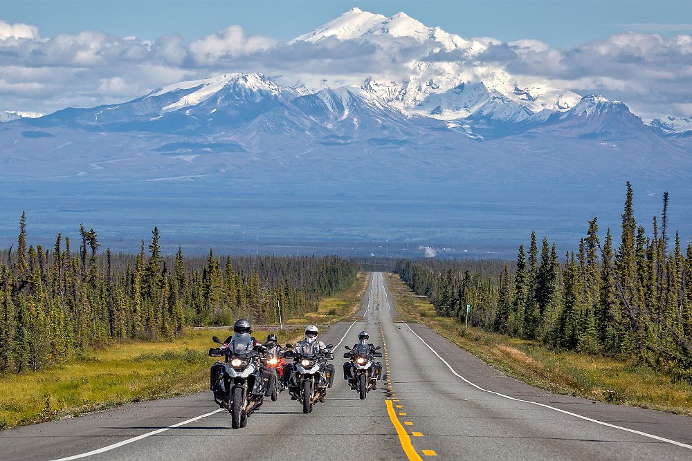 A group of riders blast down an Alaskan highway.