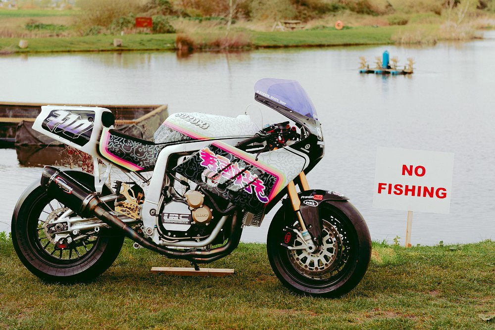 custom white sport bike parked by a lake and a 'no fishing' sign