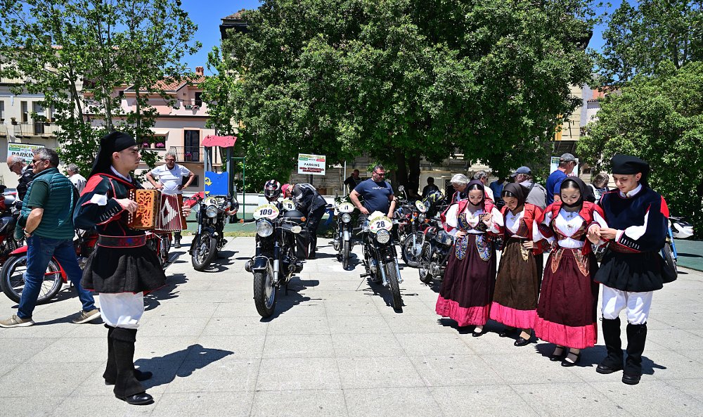 band in traditional dress playing music in a plaza in Sardinia with motorcycles around