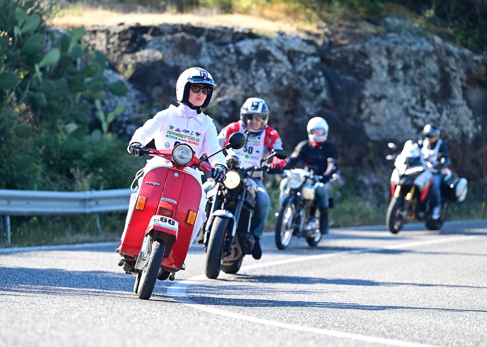 four motorcycles on the road in the Giro, from a scooter in front to a modern adventure-touring bike in the back