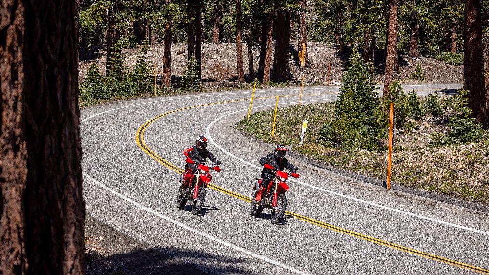 Two Desmo450 EDS riders cruise down a mountain road.