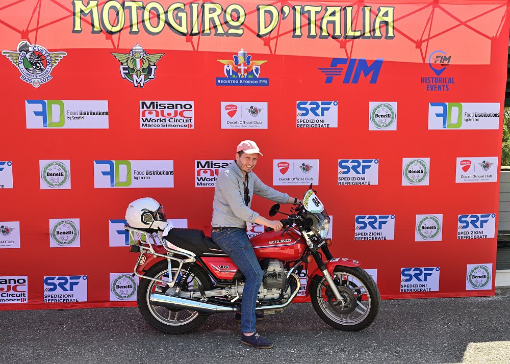 Pawel posing with his motorcycle in front of the huge MotoGiro d'Italia banner