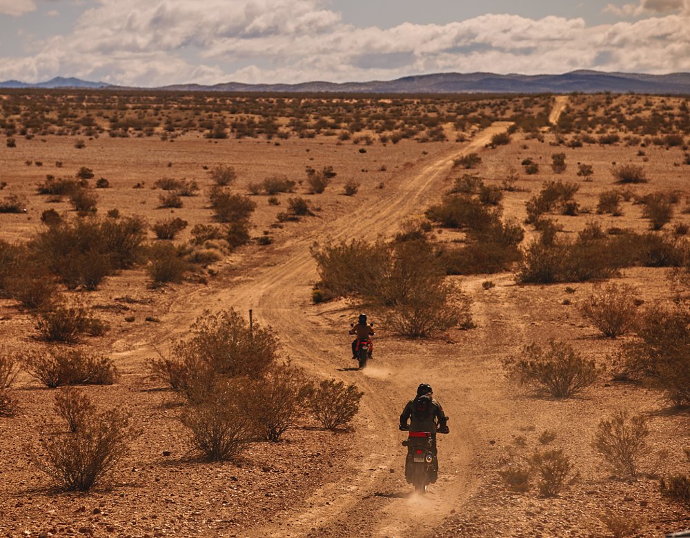 two riders on a dirt road through the desert