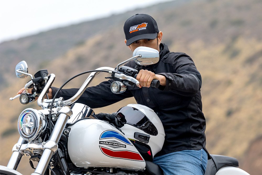 Dustin stares at the Super Glide's rear-view mirror while seated on the bike.