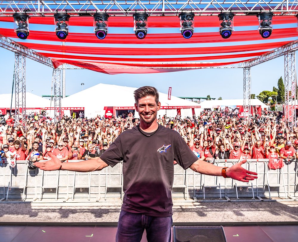 Casey Stoner spreads his arms wide and smiles before a large crowd