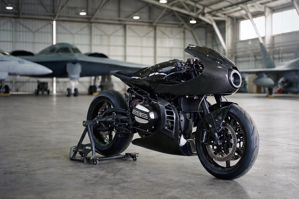 custom BMW with bullet-shaped fairing in a hangar with an airplane in the background