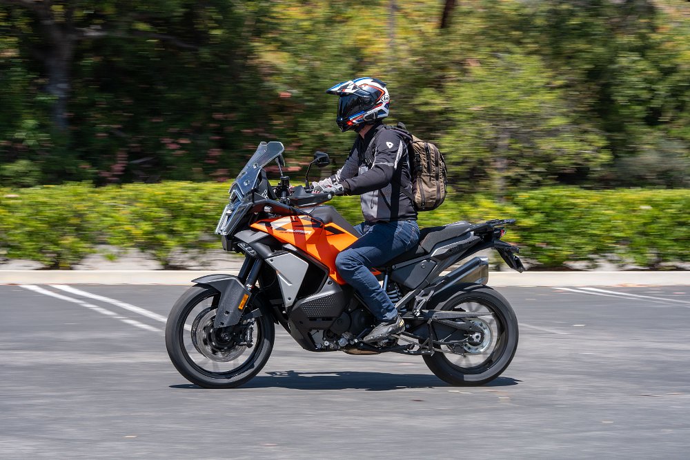2027 KTM 1390 Super Adventure S EVO riding through a parking lot.