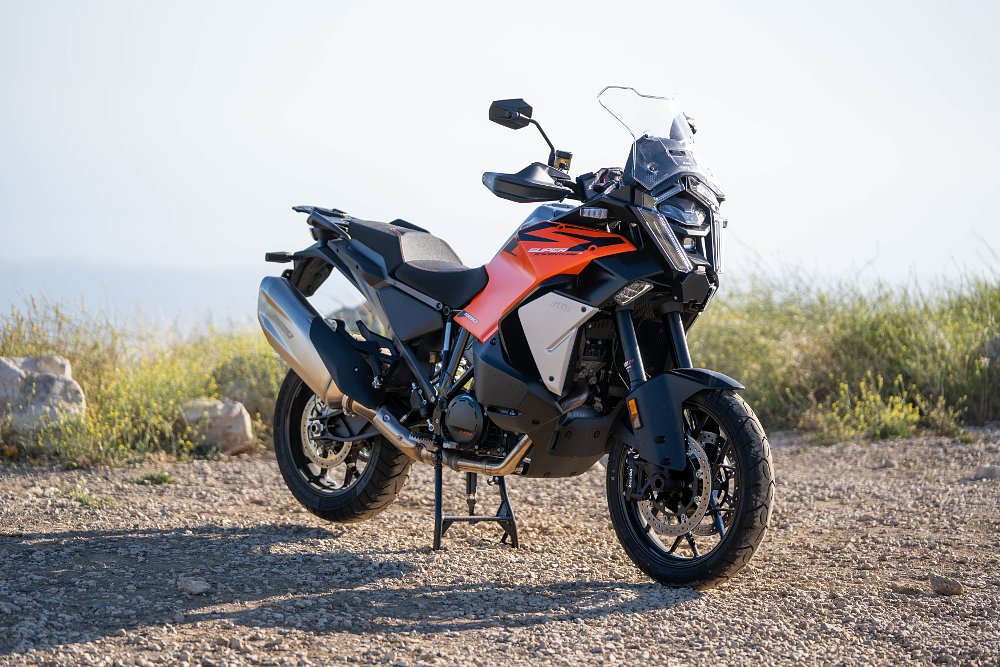 2027 KTM 1390 Super Adventure S EVO parked on its center stand in a dirt parking lot.