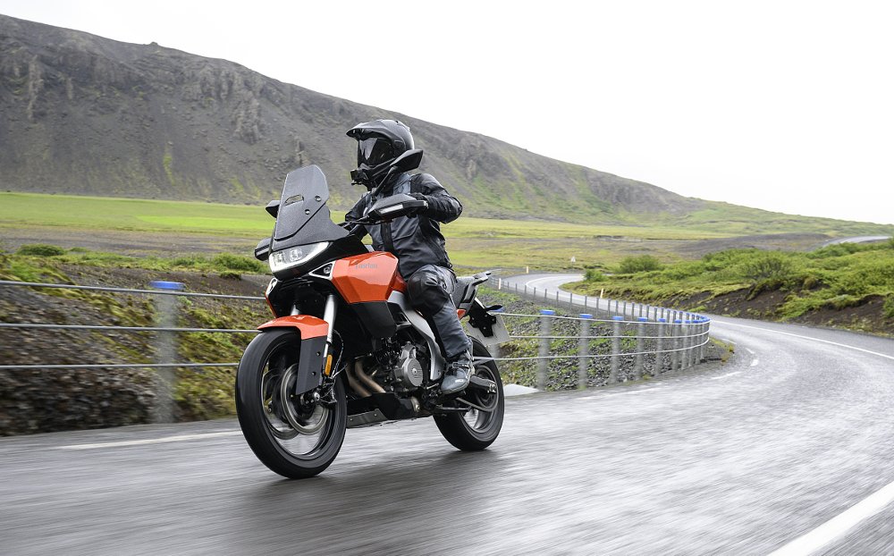 rider on the Atlas on a wet, curving road in the countryside with no trees on the bare mountains