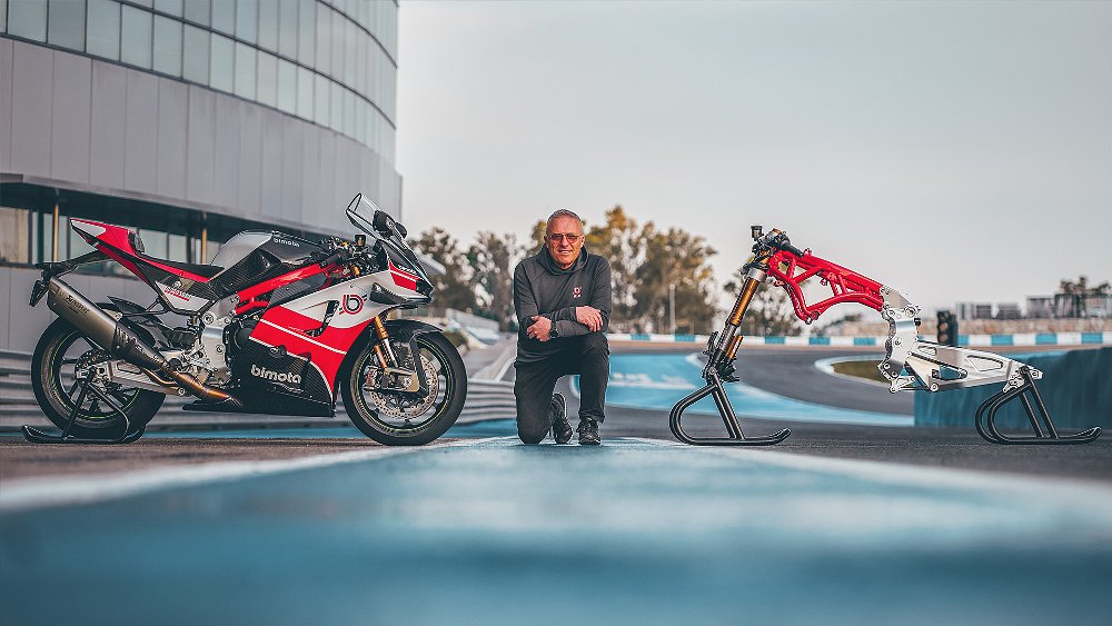 A KB998 Rimini displayed next to its naked frame in the pit lane of a race track.