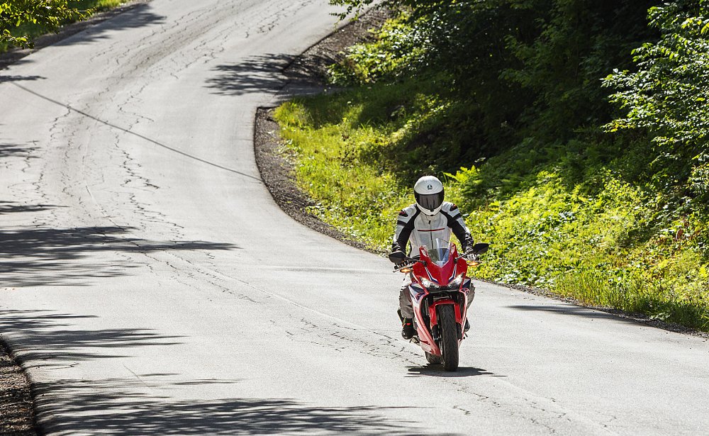 rider on the CBR500R on a small paved backroad with ripples in the pavement