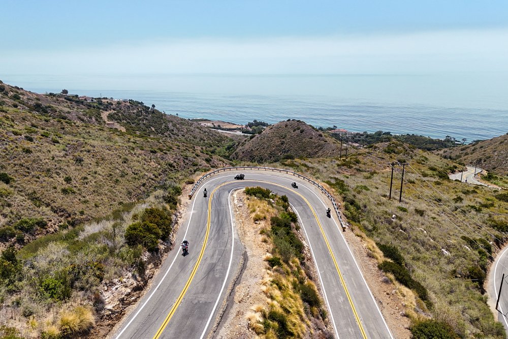 A hairpin turn on Decker Road in Malibu California, seen from above with five motorcycles riding through.
