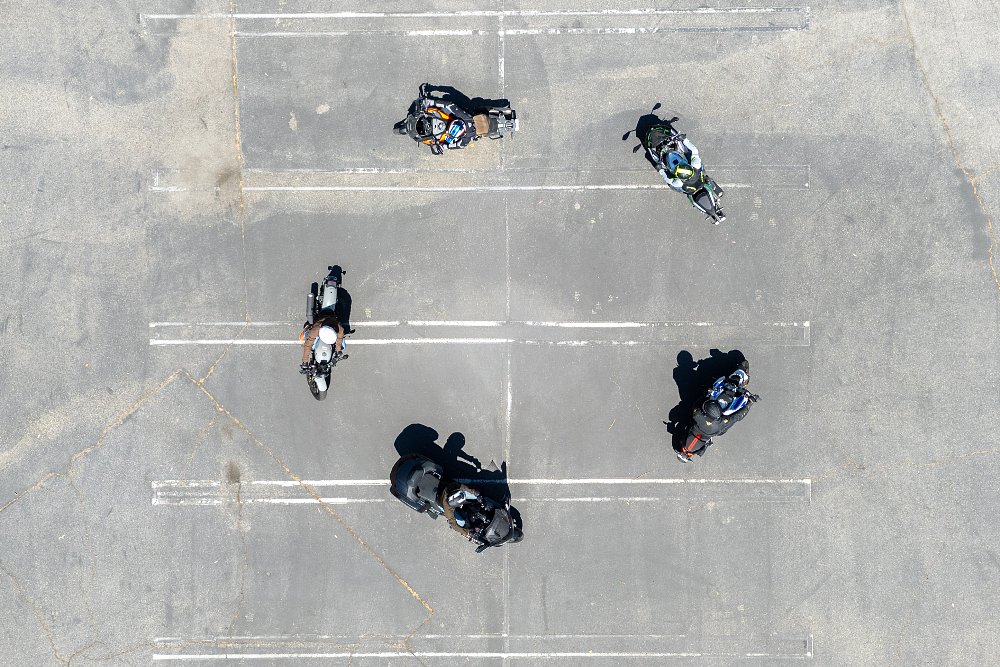 Five motorcycles riding in a circle in a parking lot, seen from above.