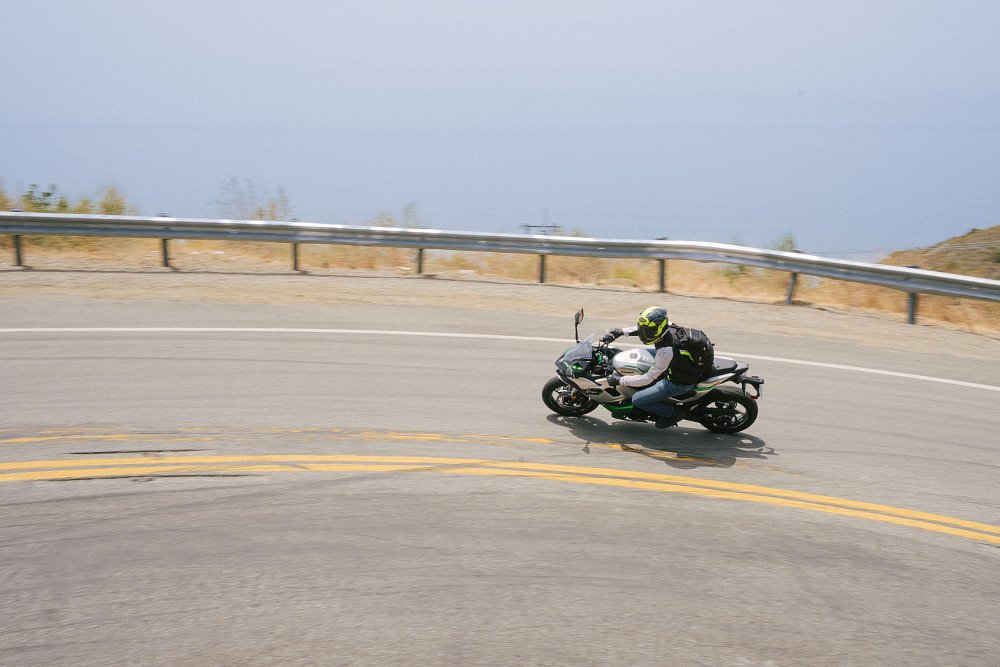 Kawasaki's Ninja 7 Hybrid riding through a left-hand curve with the ocean in the background.