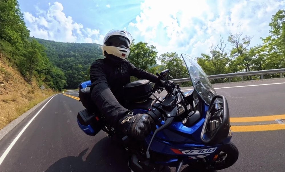 onboard view of the rider on a blue BMW R 1300 RS with another rider on the road in the distance behind