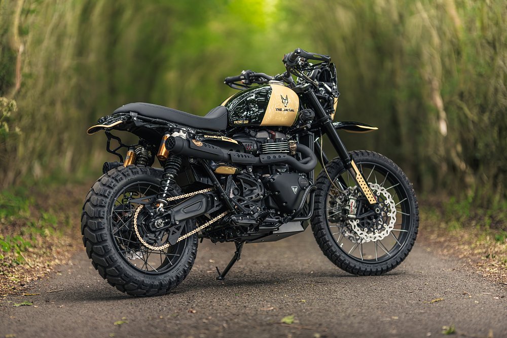 rear three-quarters view of the narrow scrambler with black paint and parts and a sand-colored band on the tank