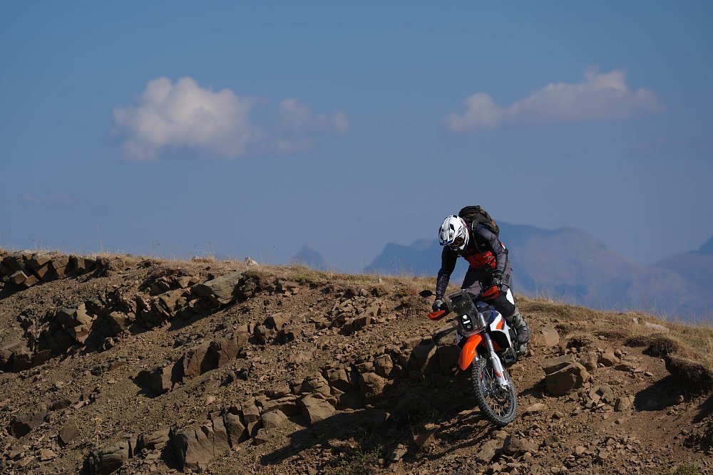 2027 KTM 690 Rally riding down a steep, rocky hill.