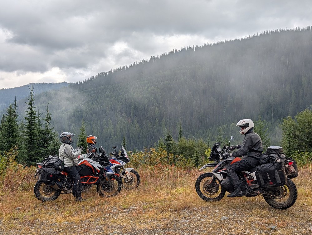 the three riders on KTMs in front of misty mountains