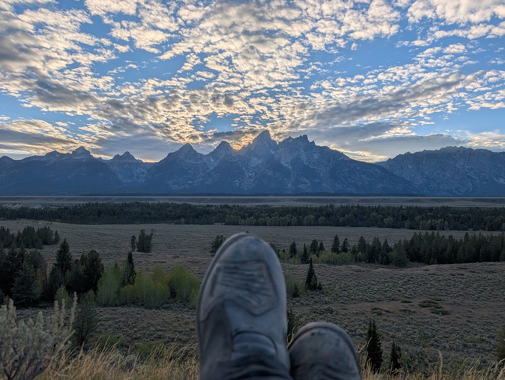 dusty motorcycle boots propped up in front of a sunset behind mountains